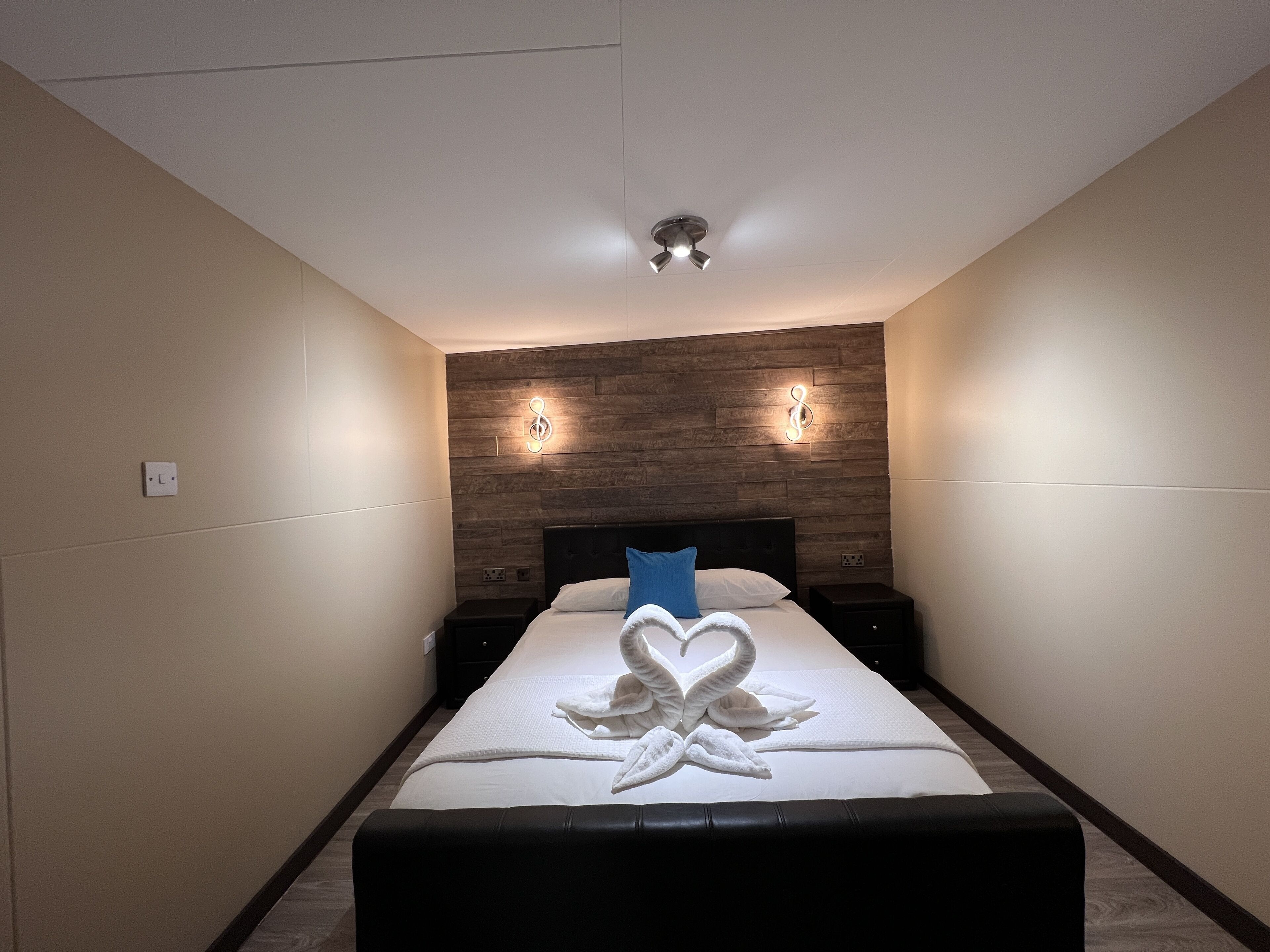 Ein Schlafzimmer mit einem Bett, einem Kopfteil, einem Nachttisch und einer Wandleuchte.
