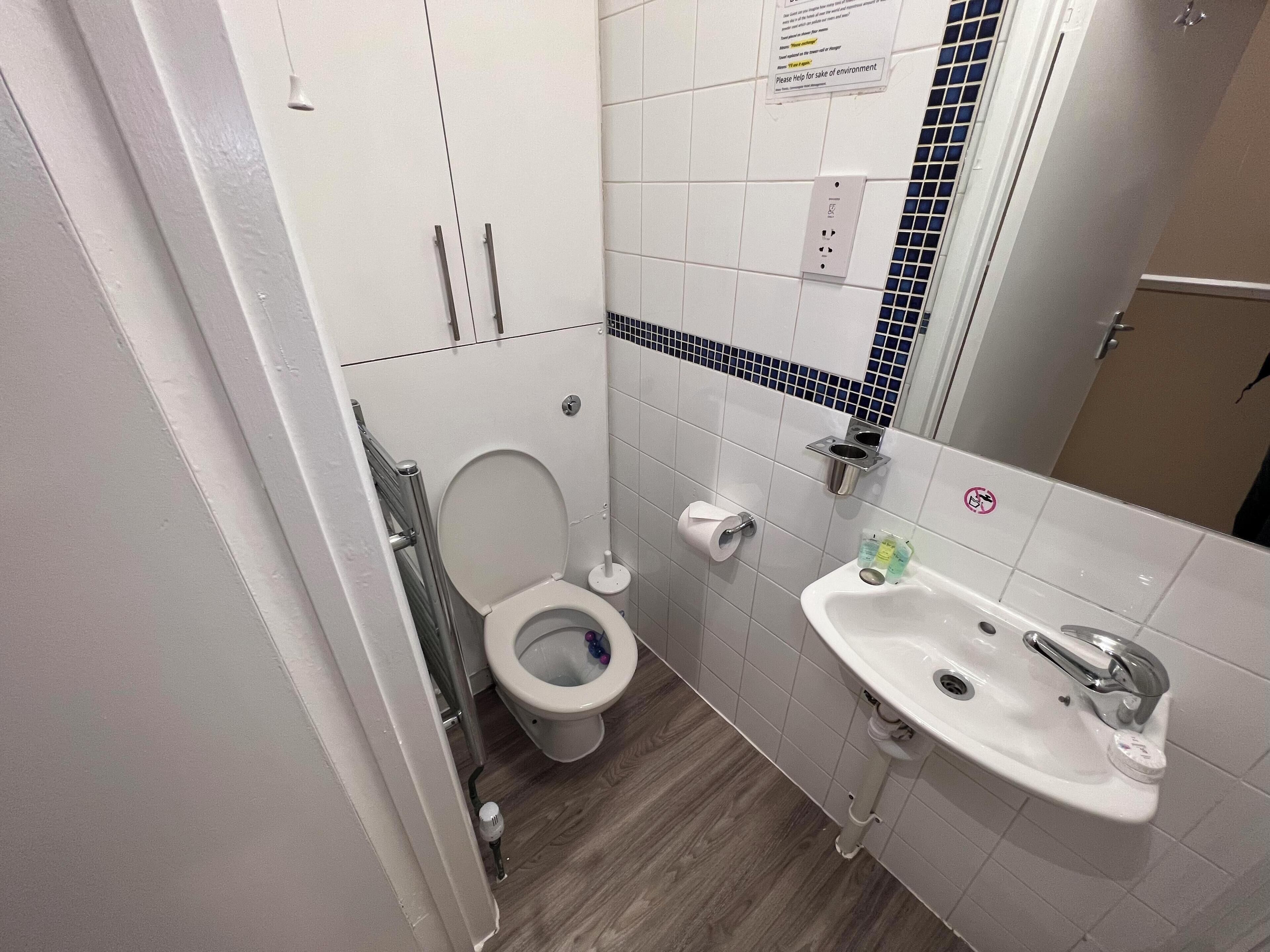 A small, clean bathroom with a toilet, sink, and mirror.