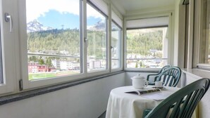 Un balcon avec une table, des chaises et une vue sur la ville et les montagnes.
