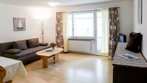 Un salon avec un canapé, une table basse, un téléviseur et un lit.
