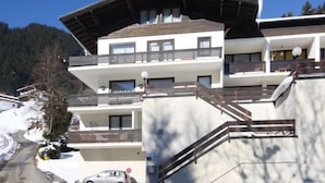 A multi-story hotel with balconies, a ski slope in the background, and a car parked in front. - Max & Moritz Top 16 by Interhome (Zell am See)