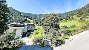 A two-story building with a sloped roof, a visible garage, and a paved driveway leading to a gated entrance. - Max & Moritz Top 16 by Interhome (Zell am See)