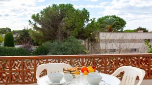 A round table with white chairs and a decorative fence in the background. - Anfora 9 by Interhome (L'Escala)