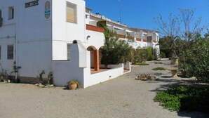 A white building with a sign reading "HINFURA" and a logo. There are multiple windows and a balcony. The building is surrounded by greenery and a gravel path. - Anfora 9 by Interhome (L'Escala)
