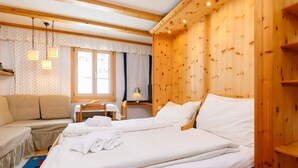 Une pièce chaleureuse, aménagée dans un chalet en bois, avec deux lits, un canapé, une table et une fenêtre.