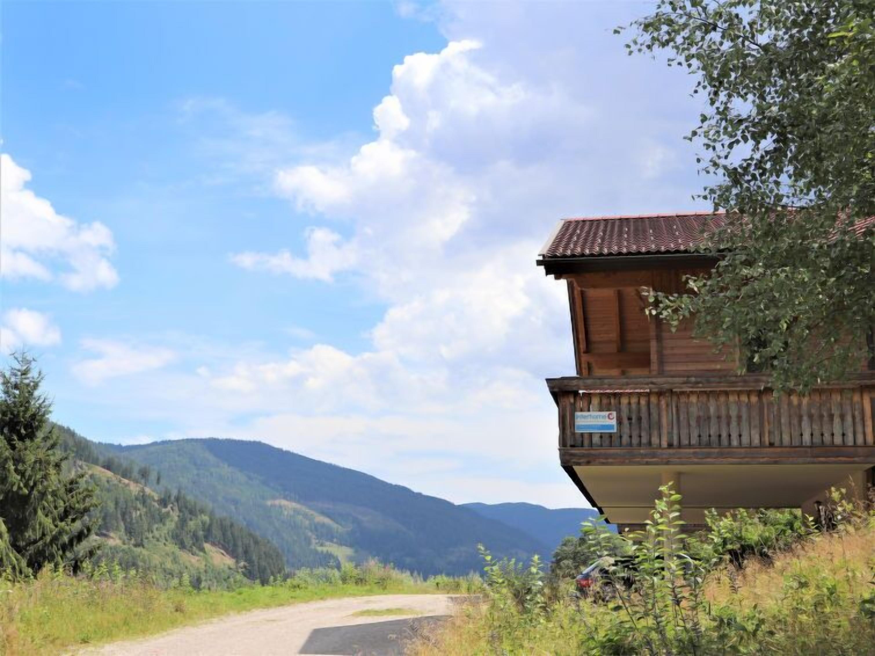 Eine Holzhütte mit einem Balkon, eingebettet in eine gebirgige Landschaft.