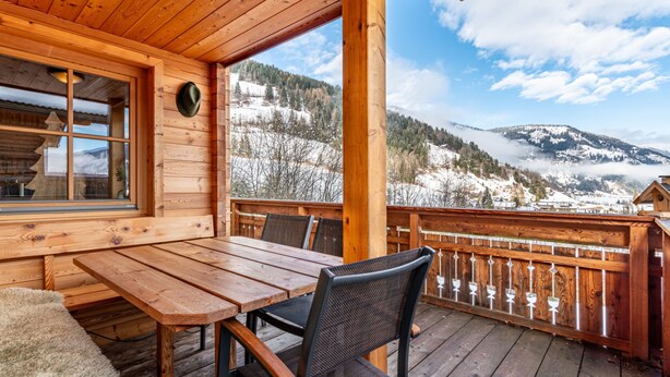 Un pontile di legno con tavolo e sedie, affacciato su un paesaggio montano innevato.