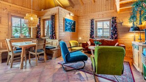 Un accogliente interno di una baita di legno con zona pranzo, posti a sedere e camino.