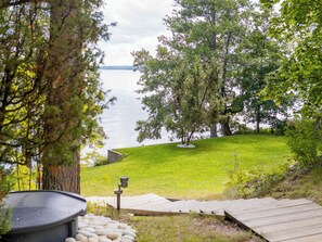 Une vue sur le lac, avec une zone herbeuse, des arbres et une terrasse en bois.