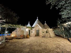 Un bâtiment en pierre doté d’une terrasse carrelée, d’une porte et d’une petite table avec des chaises.