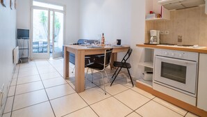 Een moderne keuken met een eethoek, een ingebouwde oven en uitzicht door een glazen deur op een terras.