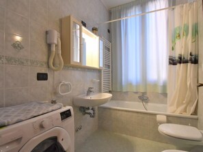 A bathroom with a washing machine, sink, toilet, and bathtub.
