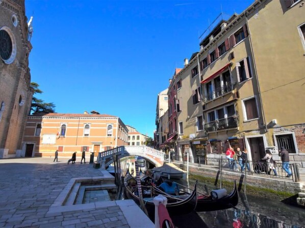 A canal with gondolas, historic buildings, and a pedestrian bridge.