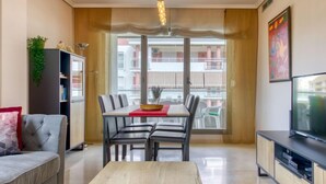 Een moderne woonkamer met een eettafel, stoelen, een bank, een televisie en een boekenkast.