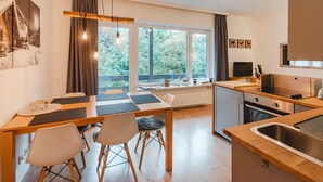 Une cuisine moderne avec un coin repas, de grandes fenêtres et une vue sur la verdure.
