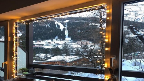 Une pièce dotée d’une grande fenêtre donnant sur un paysage enneigé avec une cascade.