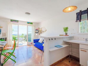 Una cocina moderna con un sofá azul, un comedor con mesa y sillas, y vistas a través de puertas de vidrio.