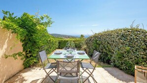 Een terras buiten met een eettafel, omringd door groen en een helder uitzicht op het landschap.
