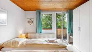 Un dormitorio con dos camas, una ventana con cortinas, un radiador y vistas a zonas verdes.