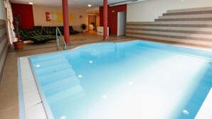 Ein Innenpool mit gefliestem Boden, roten Säulen und einer Treppe zu einer erhöhten Ebene.