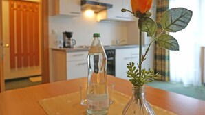 Eine Küche mit weißen Schränken, einer Kaffeemaschine und einer Wasserflasche auf der Arbeitsplatte.