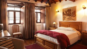 A cozy bedroom with a wooden bed, a chair, a table with a kettle, and a painting on the wall. - Casa da Eira - Turismo Rural (Lousa)