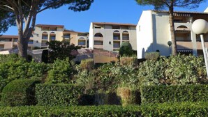 Un hôtel composé de bâtiments à plusieurs étages, doté de fenêtres en arc de cercle et d’un jardin bien entretenu, agrémenté d’arbres et d’arbustes.