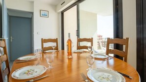 A dining table set for four with floral plates, wine glasses, and cutlery. - Le Sunset/Cap Sud by Interhome (Cap d'Agde)