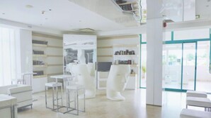 A modern interior with a minimalist design, featuring a central white sculpture, a bar area with stools, and a seating area with a glass partition.