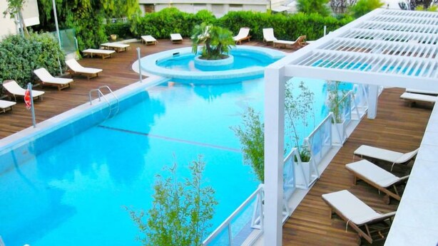 A swimming pool with lounge chairs and a pergola.