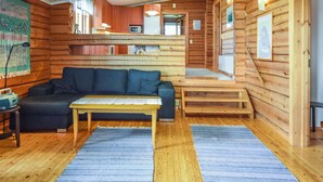 L'interno accogliente di un rifugio con una poltrona, un tavolino e una scala che conduce a un piano superiore.