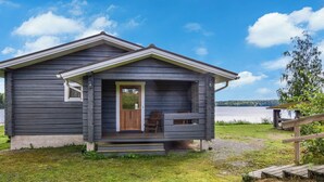Un piccolo chalet con un portico e vista su un lago.