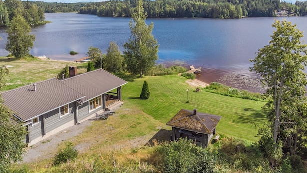 Una proprietà sul lago con una casa, un piccolo cottage e un molo che si protende nell'acqua.