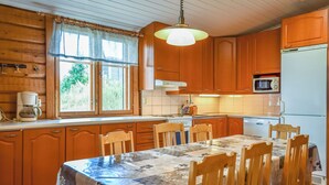 Una cucina con mobili in legno, un tavolo da pranzo con sedie, una macchina da caffè e un forno a microonde.