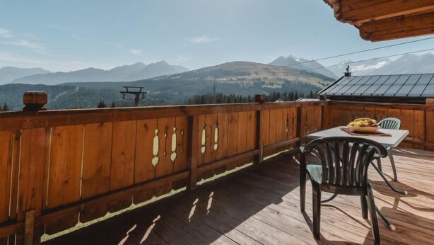 A wooden deck with a table and chairs, overlooking a mountainous landscape. - Voithofer by Interhome (Königsleiten)