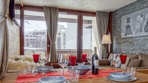 A dining area with a wooden table set for two, red wine glasses, and a bottle of wine. - Le Prariond (Val Claret) by Interhome (Tignes)