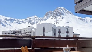 A wooden table and chair set on a balcony with a mountain view. - Le Prariond (Val Claret) by Interhome (Tignes)