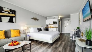 A modern hotel room with a bed, a sofa, a dining table, and a kitchen area. - Ideal Oceanview Studio Getaway! Amenities Galore (Myrtle Beach)