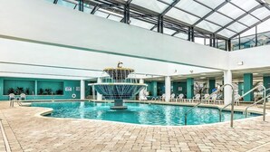 An indoor swimming pool with a central fountain, surrounded by lounge chairs and a glass ceiling. - Ideal Oceanview Studio Getaway! Amenities Galore (Myrtle Beach)