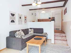Een woonkamer met een grijze bank, een houten salontafel en een trap naar een verdieping.