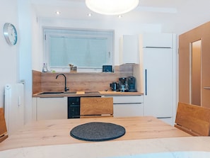 Een compacte keuken met een houten aanrecht, een spoelbak, een koffiezetapparaat en een koelkast.