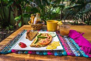 A breakfast setting with toast, fruit, and a drink on a woven placemat. - Sueno del Mar Beachfront Hotel (Tamarindo)