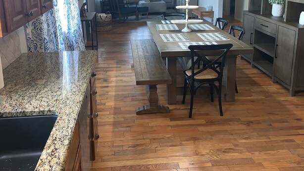 Una cocina amplia con armarios de madera, encimera de granito y un comedor con una mesa larga y sillas.