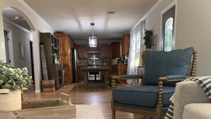 Amplia sala de estar con un ventanal grande, comedor con alacenas de madera y cocina con isla central.