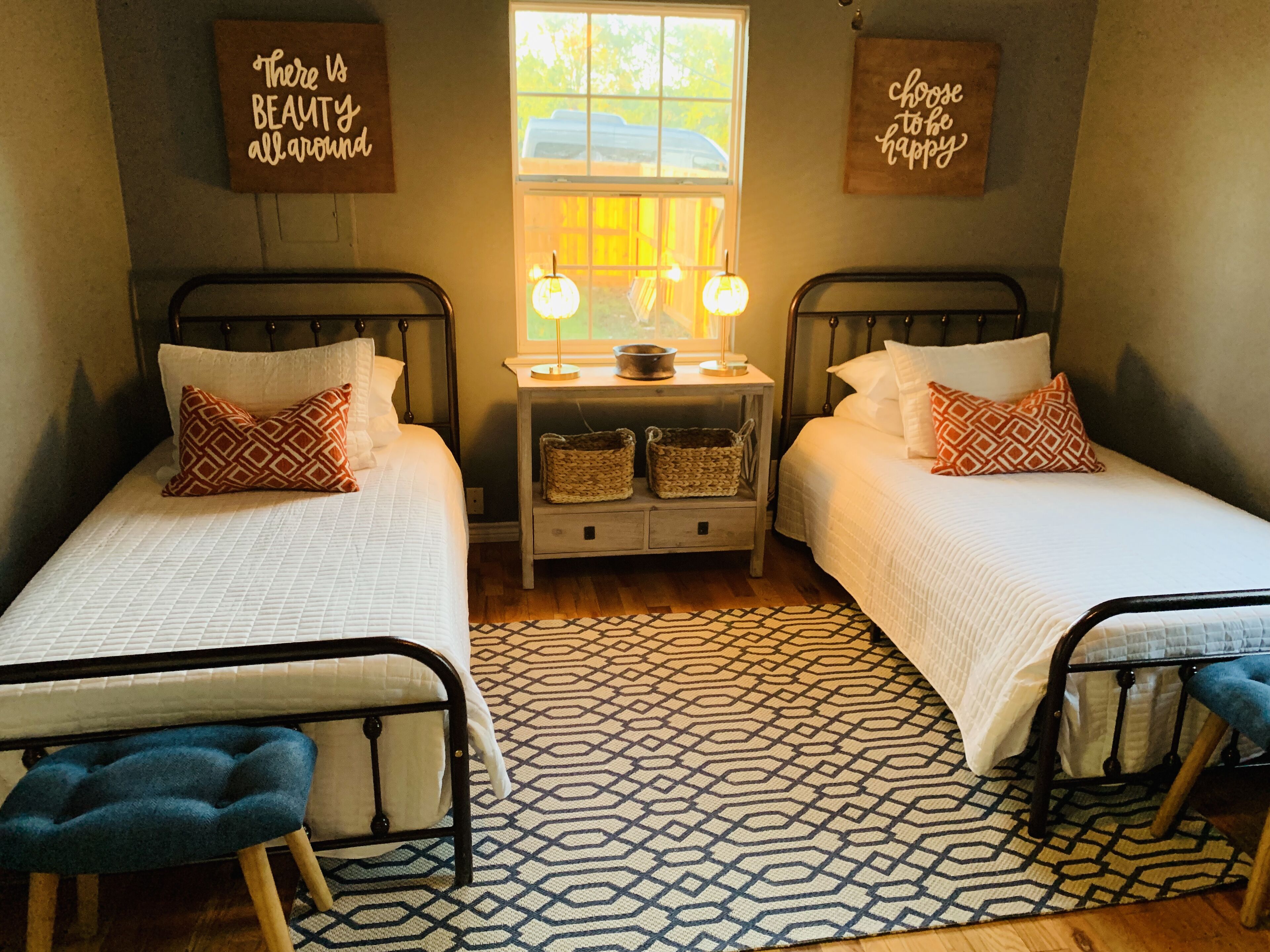 Un dormitorio con dos camas, una ventana y dos adornos en la pared.