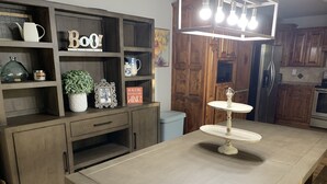 Una cocina con armarios de madera, una isla central con una lámpara y un expositor para pasteles de estilo vintage.