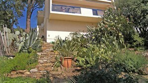 Un edificio de varios pisos con balcones, rodeado de cactus y otra vegetación desértica.