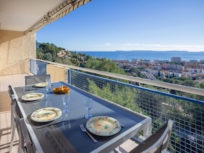 Un balcon avec une table dressée pour le dîner, offrant une vue sur le paysage urbain de la côte.