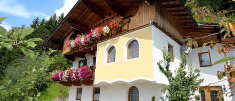 A two-story building with a sloped roof, wooden balcony railings, and flower boxes.