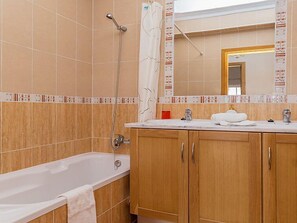 Une salle de bain avec une baignoire, des meubles en bois, un lavabo avec un miroir et une douche.